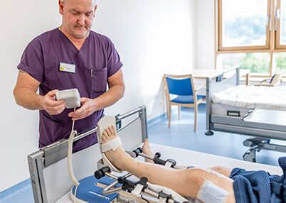 Physiotherapeut bei Patienten nach Knie-OP.